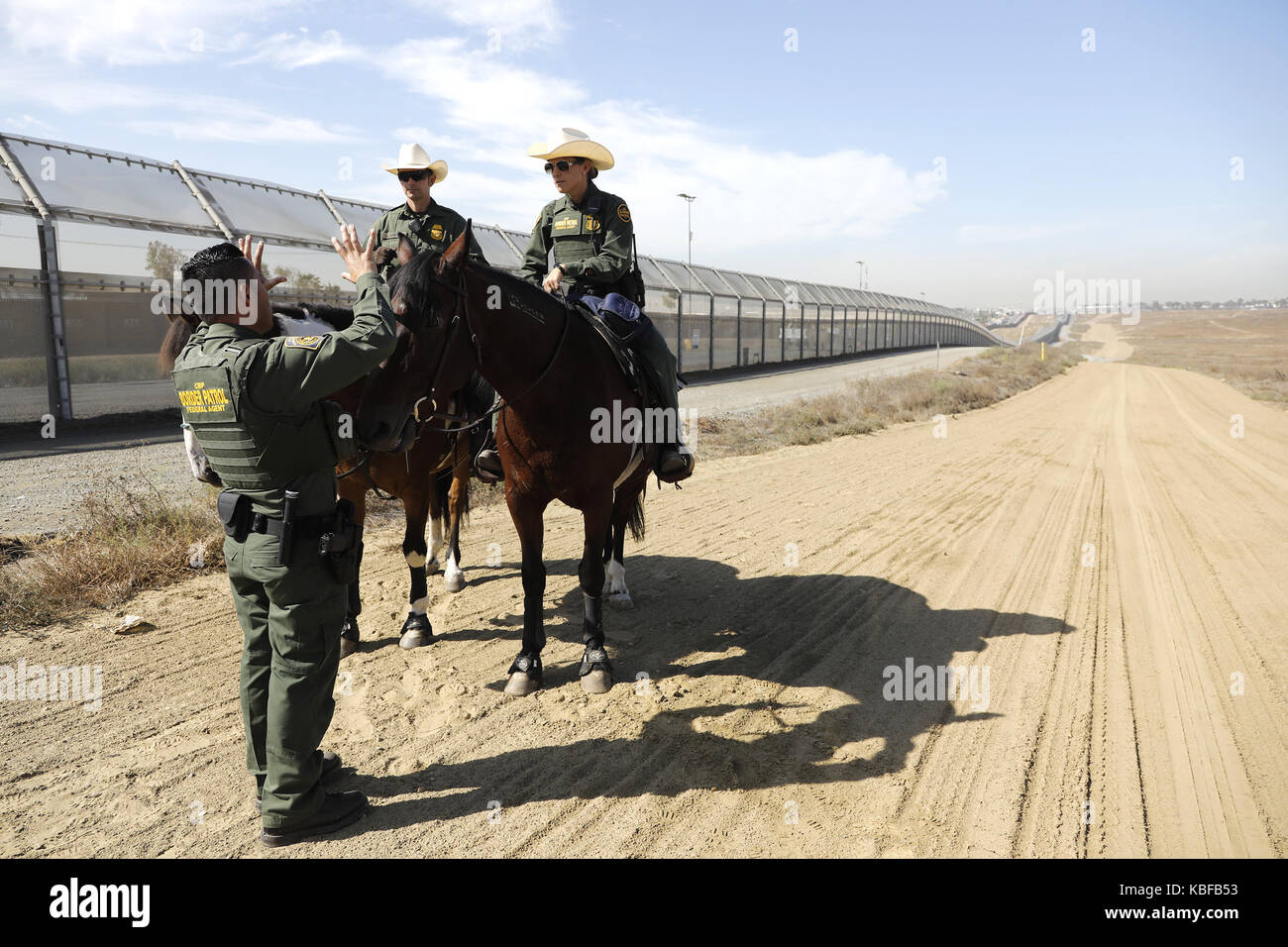 San Diego, USA. 29 Sep, 2017. US Border Patrol-Agenten Saul Rocha, Links, stoppt Hallo Kollegen Grenze Patrouille Offiziere auf dem Rücken der Pferde in der Nähe des sekundären Grenzzaun zu Mexiko zu sagen. Beiden Vertragspartnern der Regierung begann mit dem Bau von Prototypen der vorgeschlagenen Grenzmauer Präsident Donald Trump mit Mexiko in dieser Woche, acht Modelle werden schließlich in einer abgelegenen Gegend von San Diego östlich der Otay Mesa Grenzübergang errichtet werden. Zoll- und Grenzschutz kann mehrere Gewinner oder Keine auswählen. Credit: ZUMA Press, Inc./Alamy leben Nachrichten Stockfoto