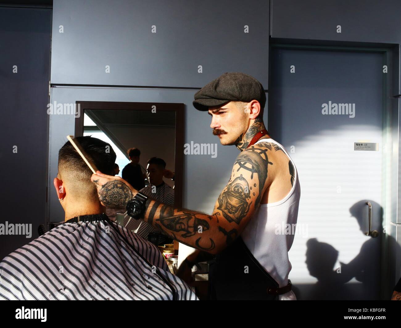 Hongkong. September 2017. Ein Friseur mit Tattoos und Schnurrbart fixiert die Haare eines Kunden während der Hong Kong Tattoo Convention 2017. Quelle: Gonzales Photo/Alamy Live News Stockfoto