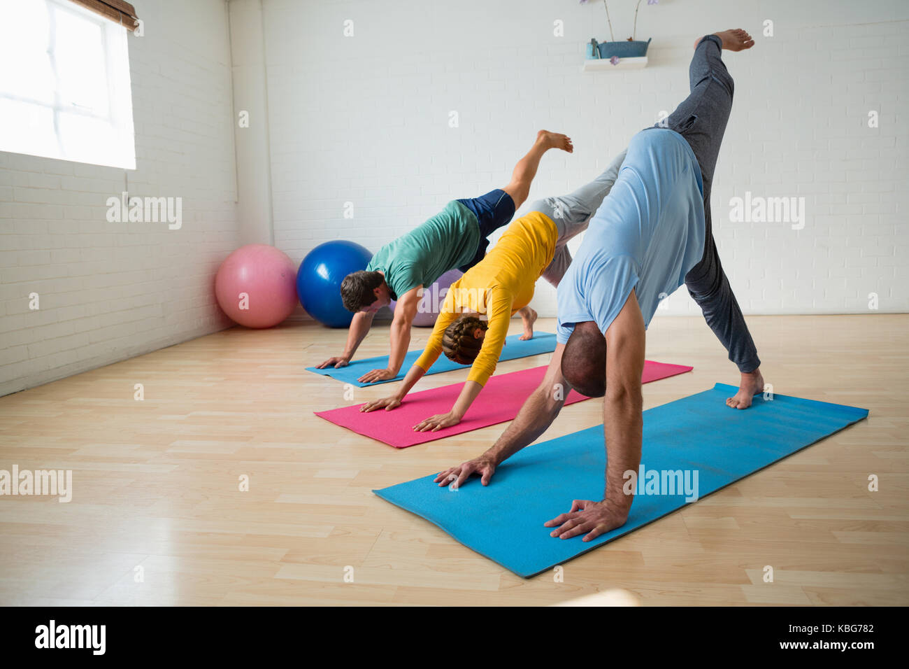 Lehrer mit Schüler üben in den nach unten schauenden Hund pose mit Füßen auf Yoga Studio Stockfoto