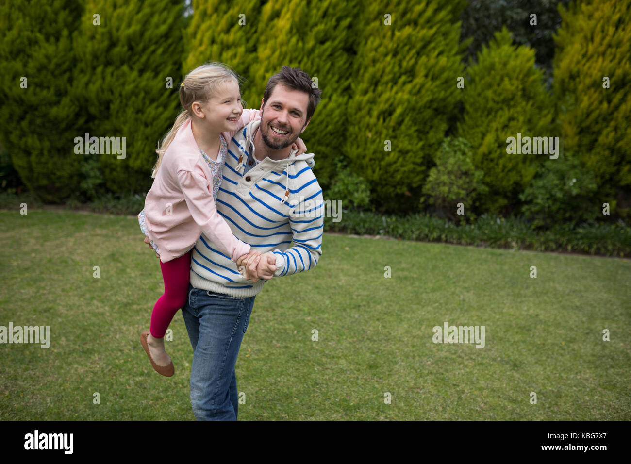 Junge Mädchen tanzen mit ihren Vätern Schultern im Park Stockfoto