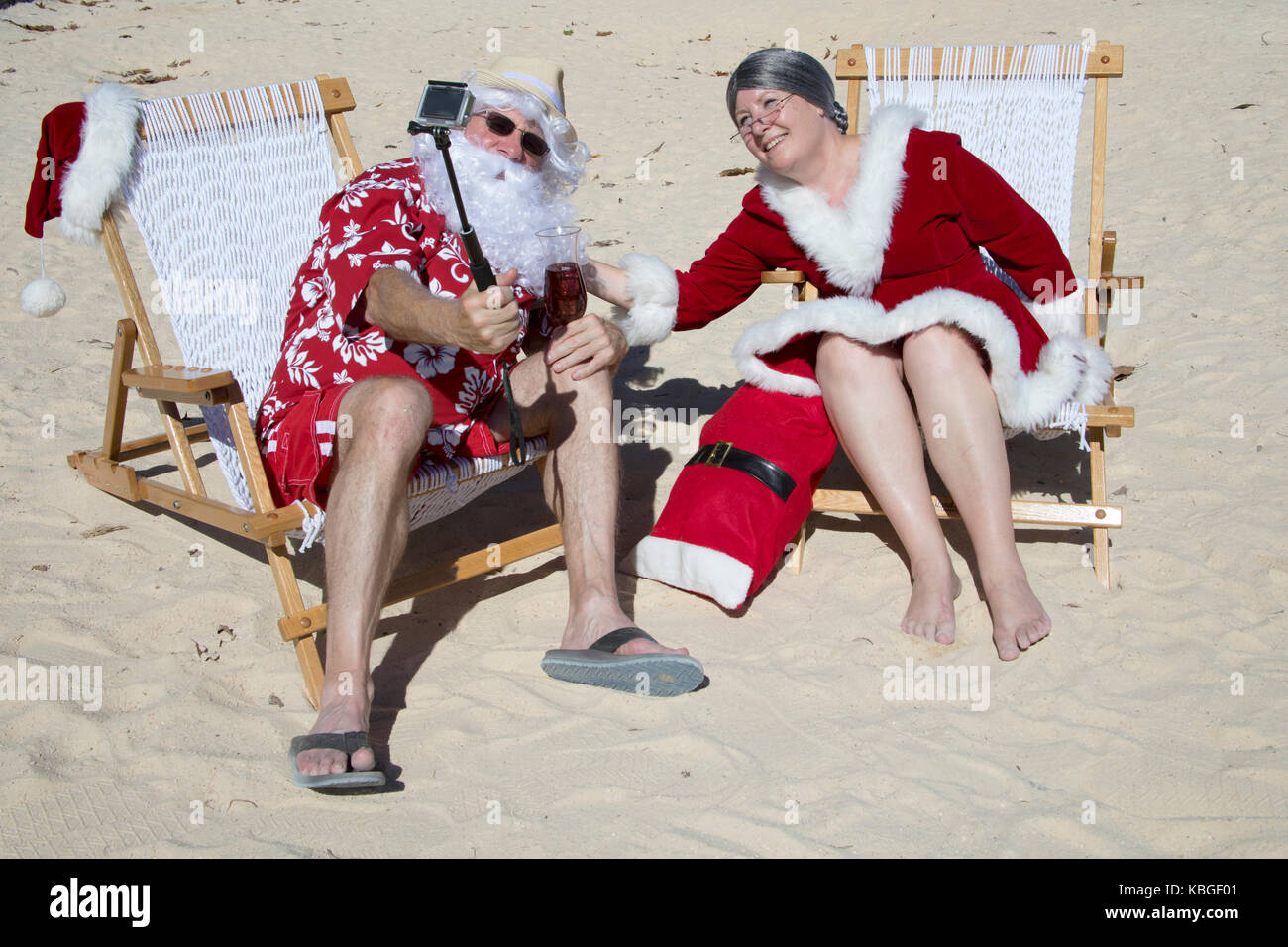 Weihnachtsmann in rot Badehose und Hawaiian shirt am Sandstrand mit Frau Claus unter selfie. Stockfoto