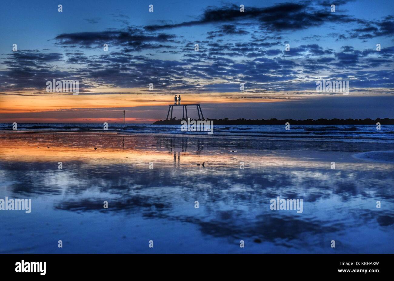 Die Herbstsonne geht über der Nordsee vor dem Paar des Künstlers Sean Henry in Newbiggin-by-the-Sea, Northumberland, auf, da Großbritannien auf Kurs ist für heftige Regenfälle und Stürme, während Überreste des Hurrikans Lee "extra Oomph" zu einem Niederdrucksystem hinzufügen, das sich über den Atlantik bewegt, sagten Prognostiker. Stockfoto