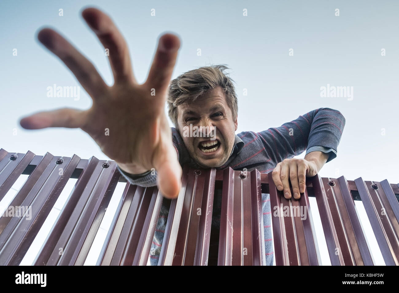 Zornigen Mann wütend klettert über den Zaun und brechen die Grenzen des privaten Eigentums und seine Hand nach unten ziehen. Stockfoto