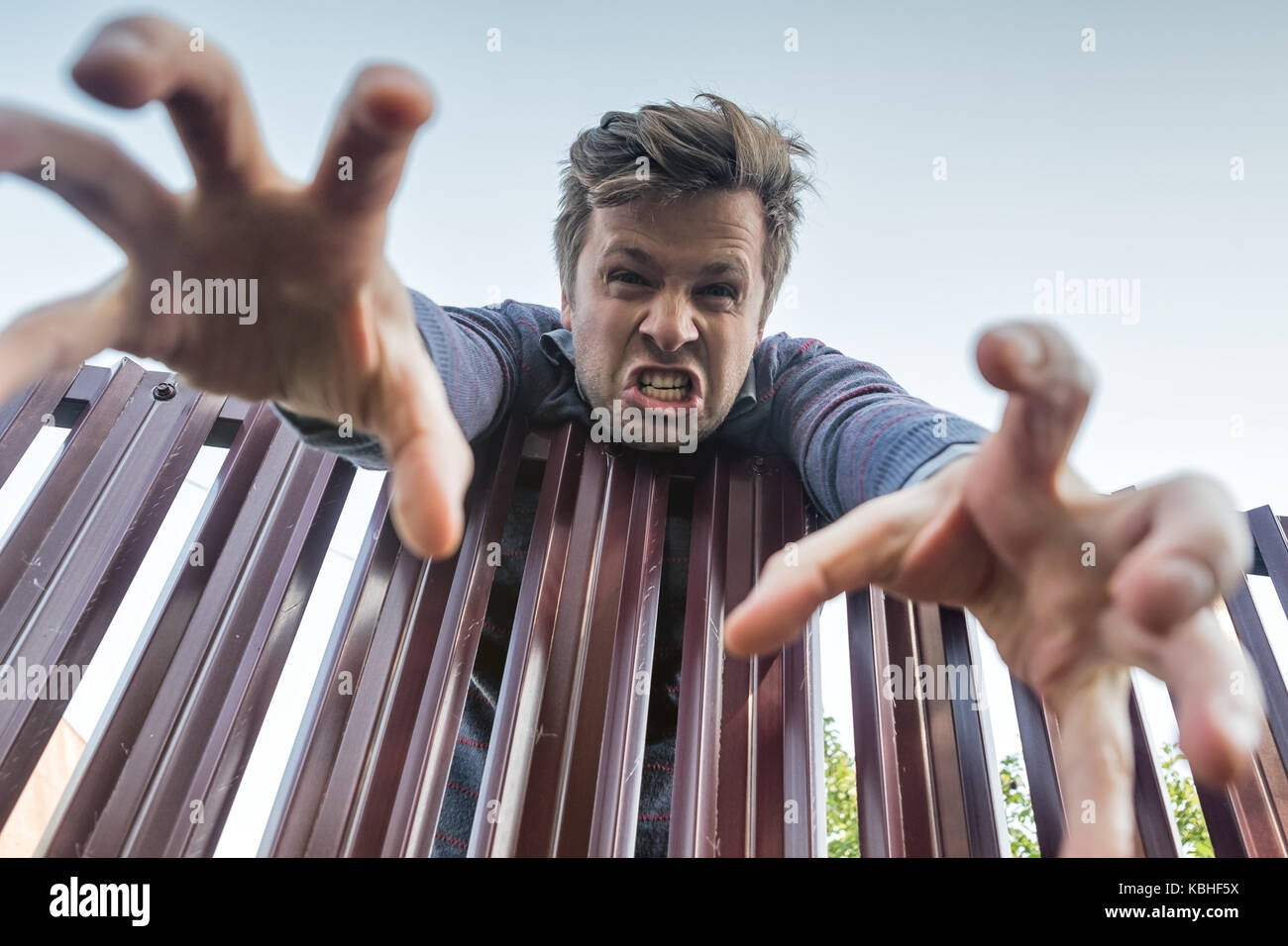 Zornigen Mann wütend klettert über den Zaun und brechen die Grenzen des privaten Eigentums und seine Hand nach unten ziehen. Stockfoto