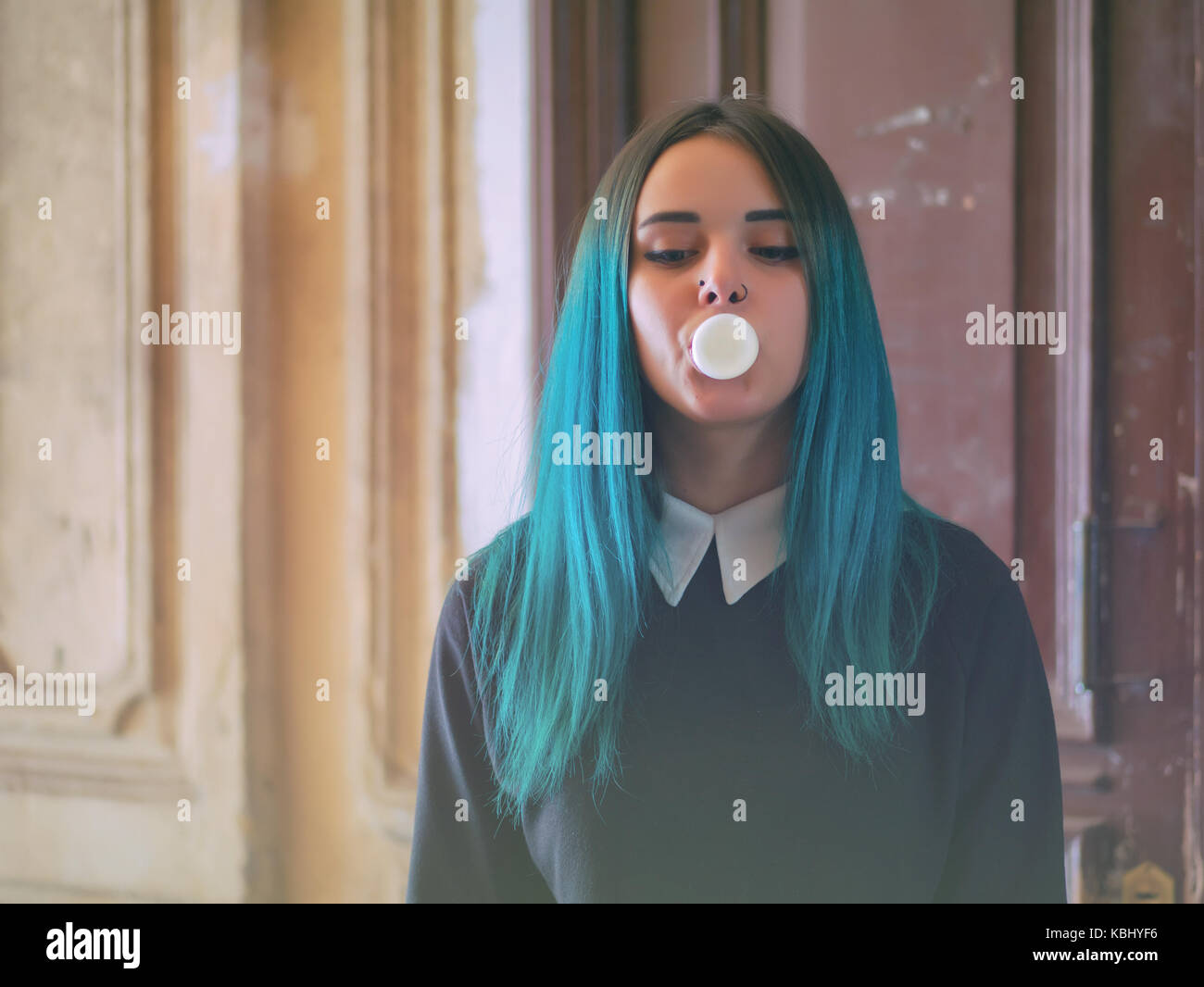 Cute gotischen Modell bläst bubblegum. Street Punk oder Hippie Studentin mit blau bunt gefärbte Haare, Piercing, Objektive, Ohren Tunnel und ungewöhnliche hairsty Stockfoto