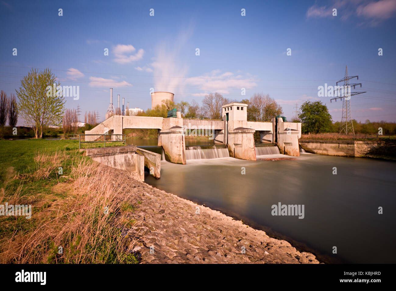 Tagsüber lange Belichtung einer Wehr, ein Kraftwerk im Hintergrund. Stockfoto