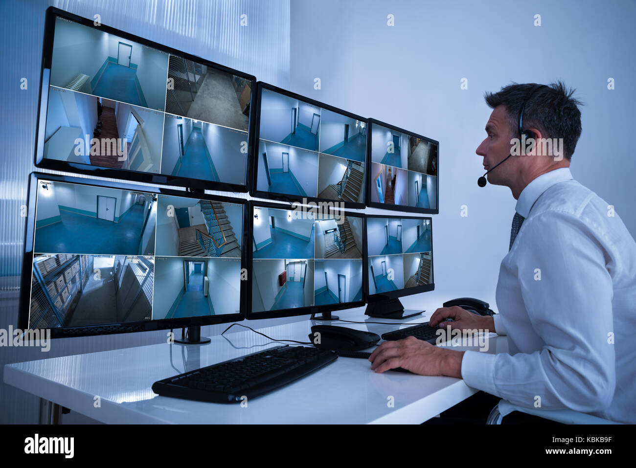 Ansicht der Rückseite des Security System Operators an CCTV-Aufnahmen am Schreibtisch im Büro suchen Stockfoto