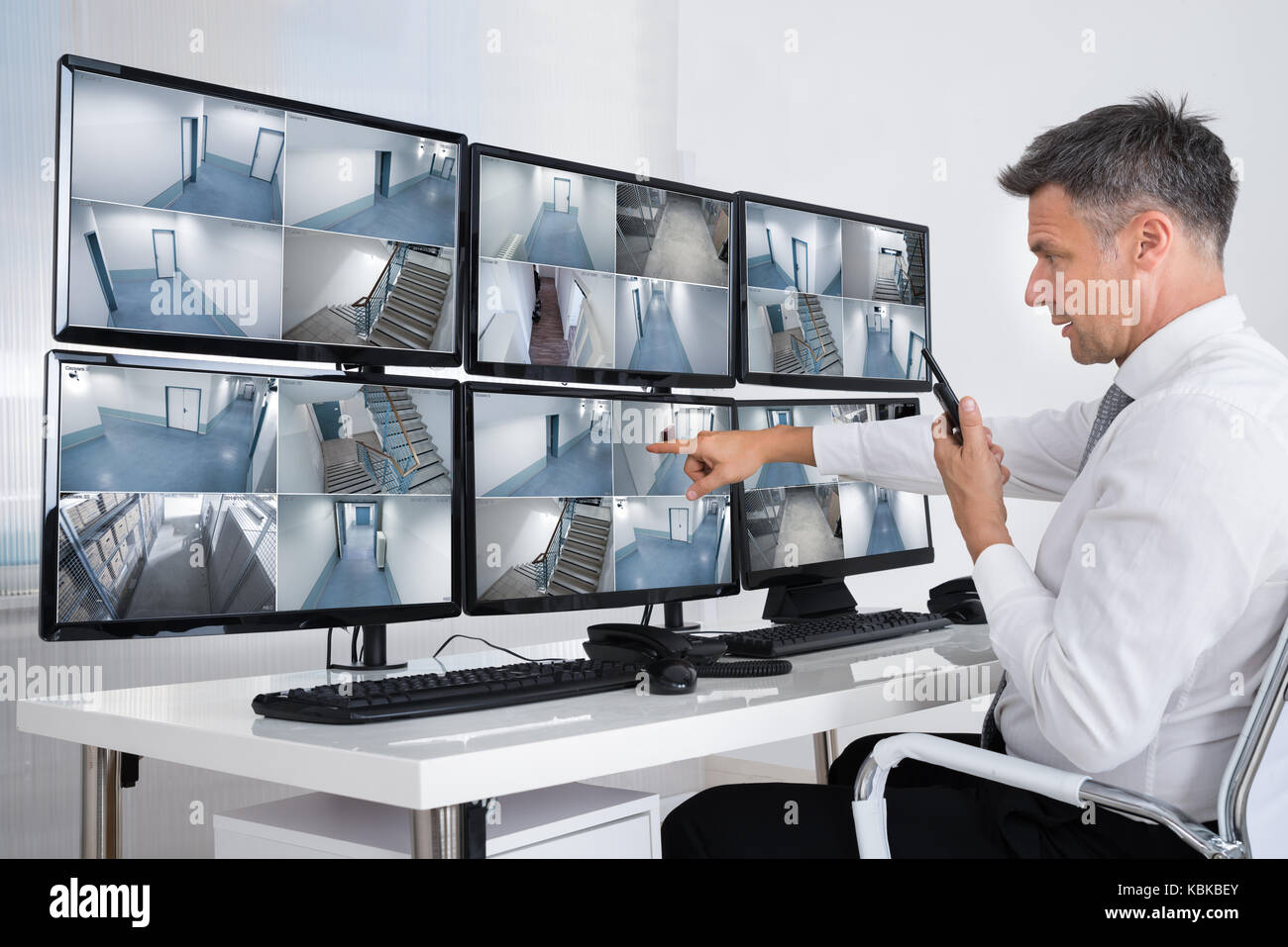 Seitenansicht des Security System Operator mit walkie-talkie bei CCTV-Aufnahmen suchen Stockfoto