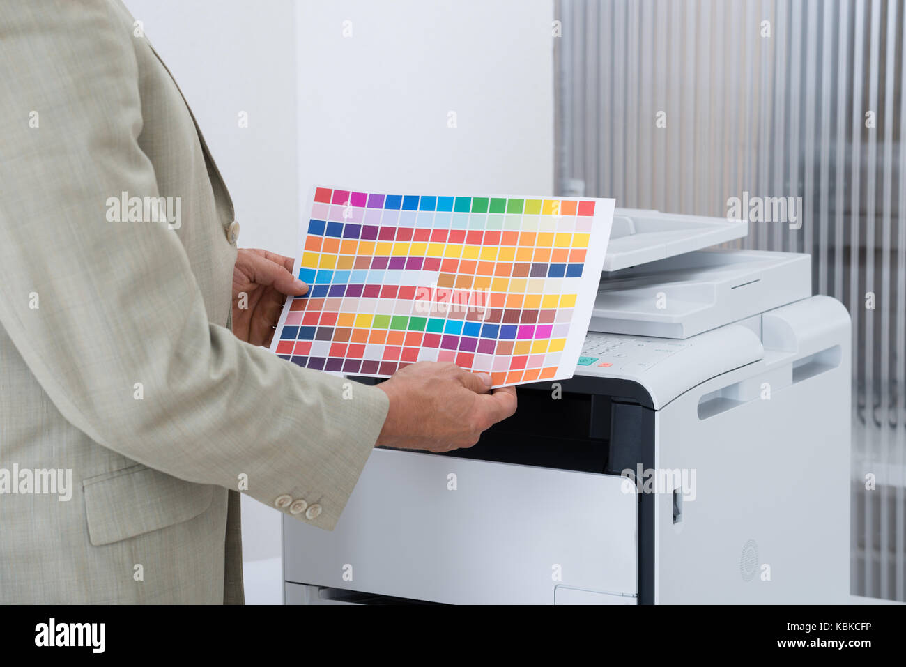 Mittelteil der Geschäftsmann Holding multi farbiges Papier durch Drucker im Büro Stockfoto