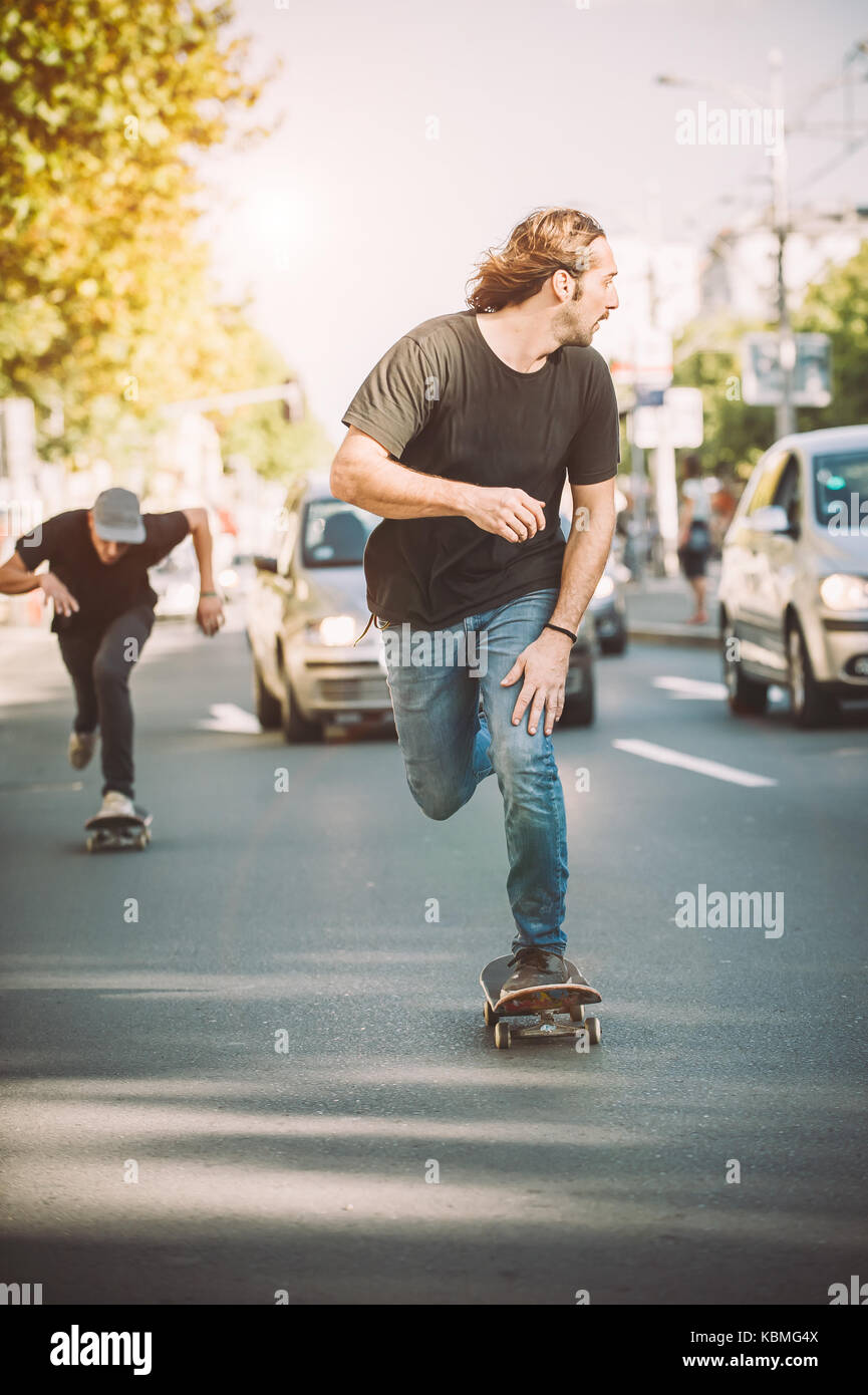 Zwei pro Fahrt skate Skateboard Fahrer vor dem Auto auf die Stadt Straße  Straße durch Stau Stockfotografie - Alamy