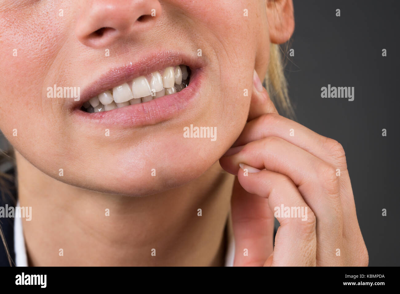 7/8 Image der jungen Geschäftsfrau Leiden von Zahn ache über grauer Hintergrund Stockfoto