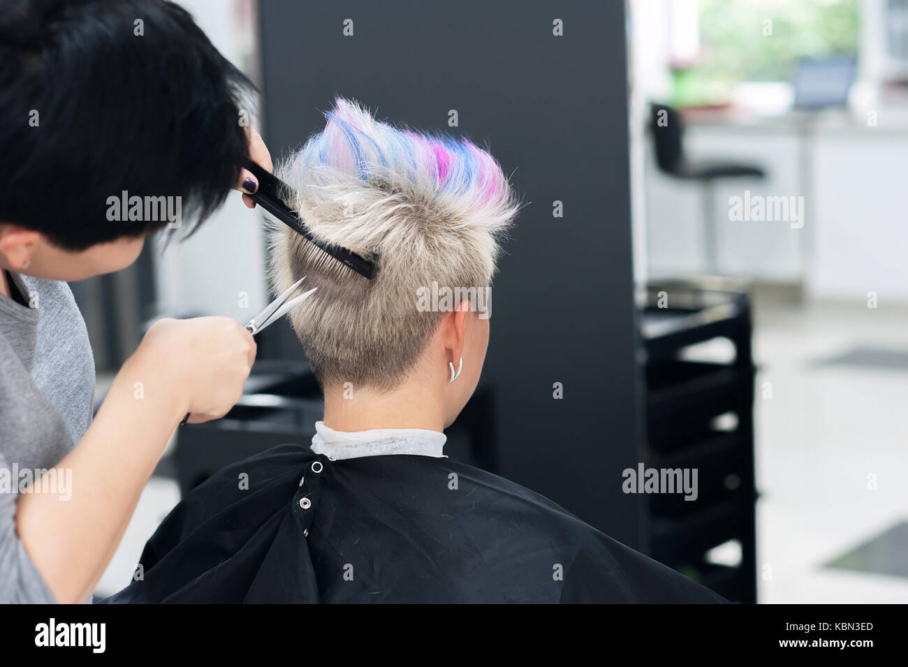 Damen Haarschnitt. Friseur, Beauty-Salon. Professioneller Friseur machen stilvolle Frisur. Friseur schneiden Frau knallt Haar. Prozess der Haare schneiden Stockfoto