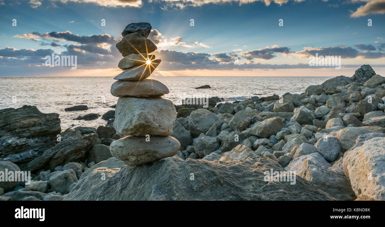 Rock Balancing bei Sonnenuntergang in einem Rocken Ende, Isle of Wight, England Stockfoto