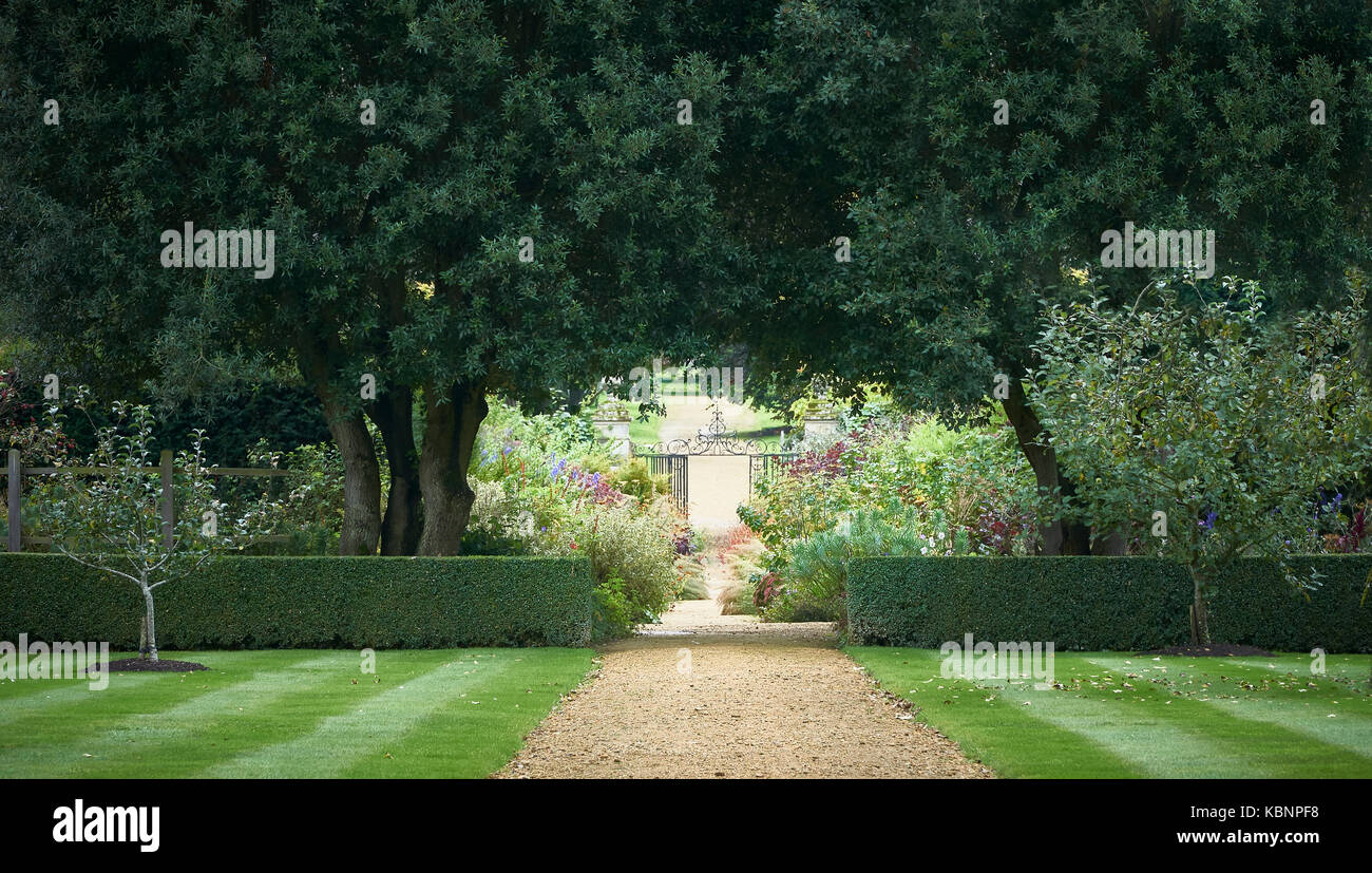Weg zu einem reich verzierten schmiedeeisernen Tor, durch Gärten Stockfoto