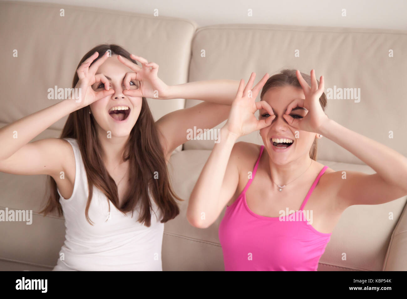 Zwei Freundinnen, indem Sie eine Schutzbrille mit Fingern albern. Stockfoto