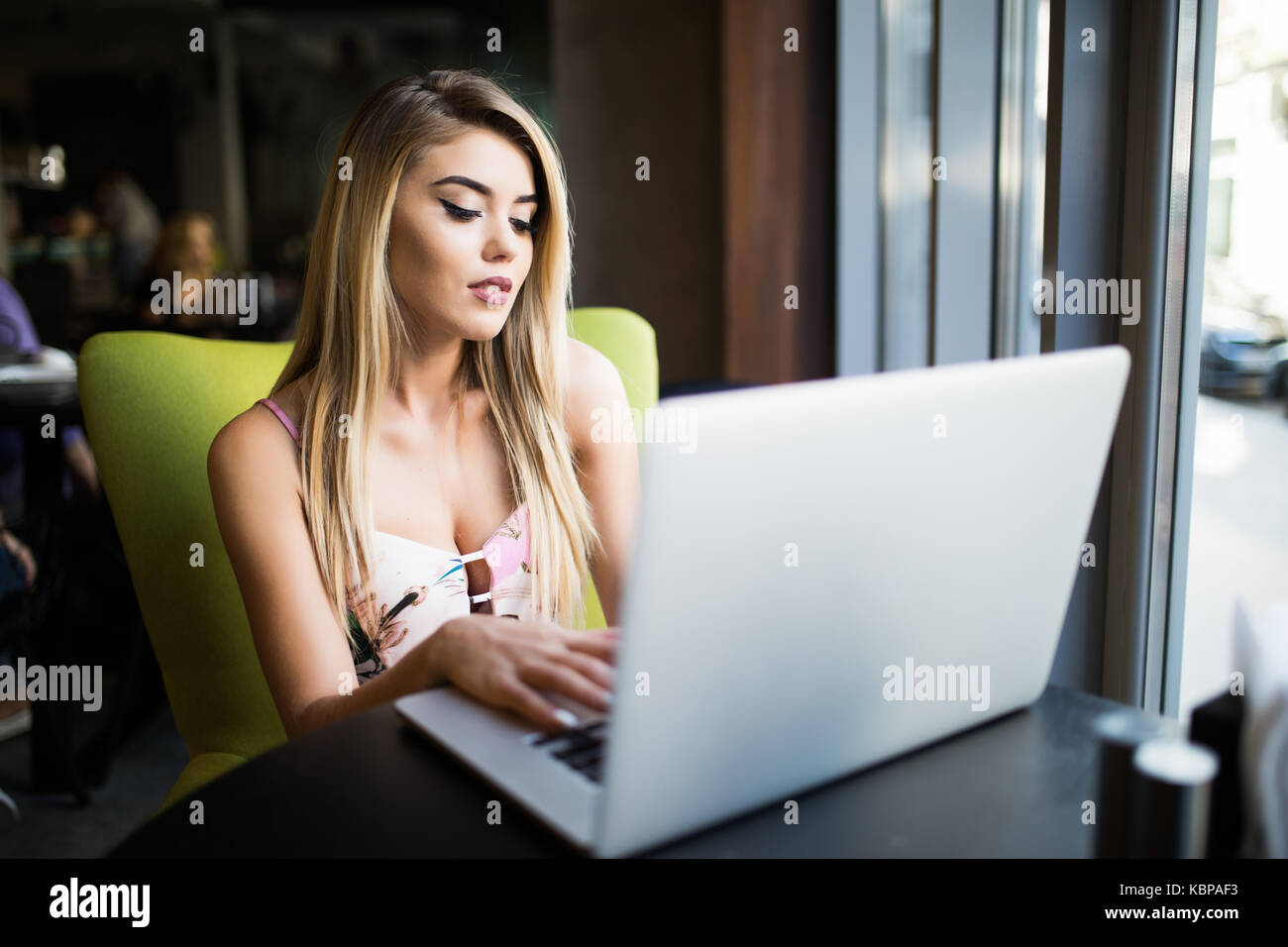 Schöne kaukasische Frau träumt von etwas, während mit tragbaren Net sitzen - buchen Sie im modernen Cafe Stockfoto