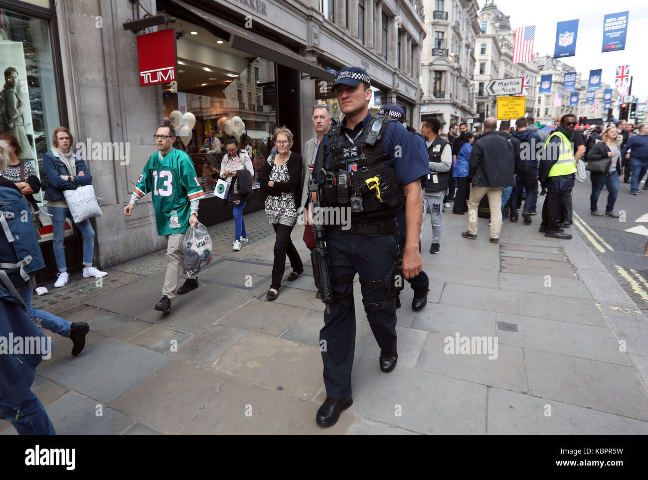 Bewaffnete Polizei Spaziergang unter den amerikanischen Fußball-Fans auf Regents Street in London, vor einer Feier des American Football. Stockfoto