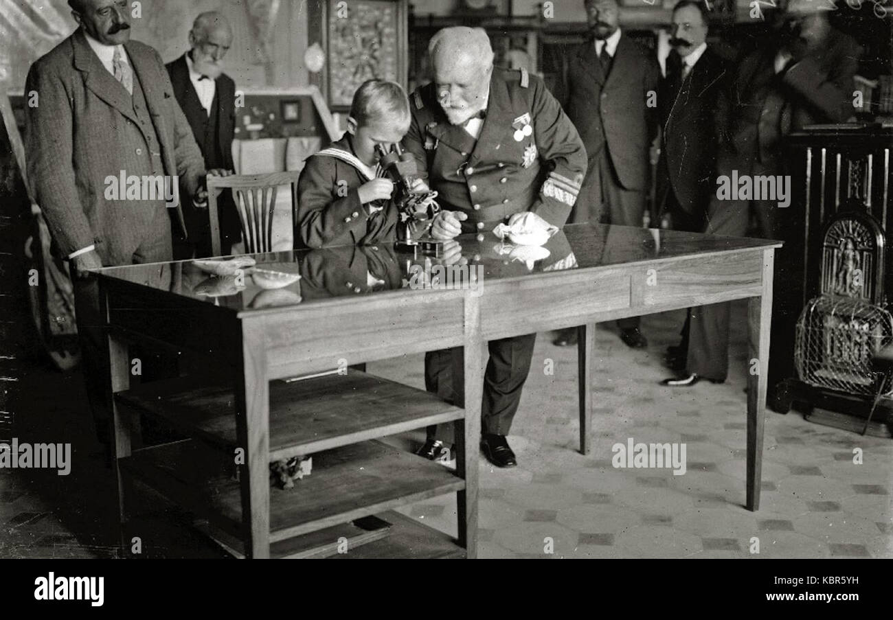 Dieses historische Bild zeigt den Infanten Don Alfonso mit General Mata, die beide durch ein Mikroskop beobachten. Das Foto zeigt einen Moment in der Geschichte mit spanischen Adel- und Militärfiguren aus dem 19. Jahrhundert. Stockfoto