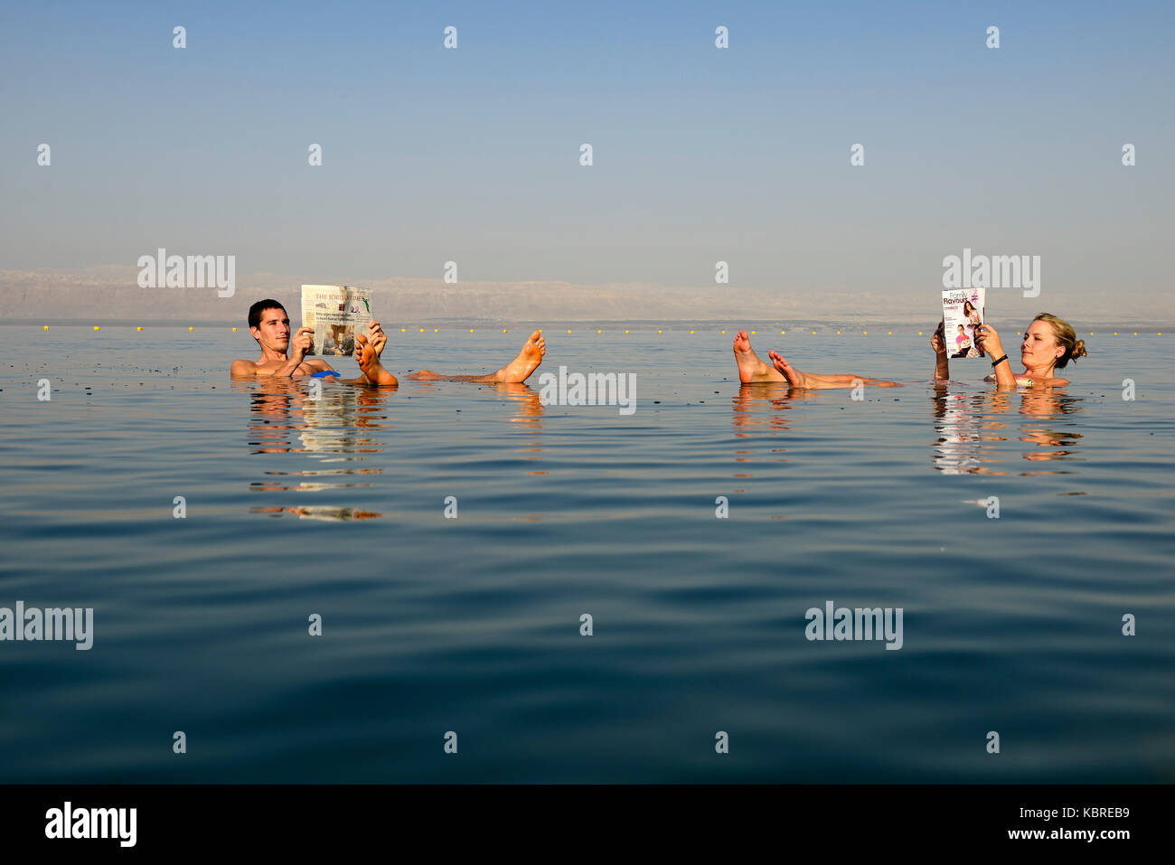 Junges Paar liest Zeitung floating in Totes Meer, Jordanien Stockfoto