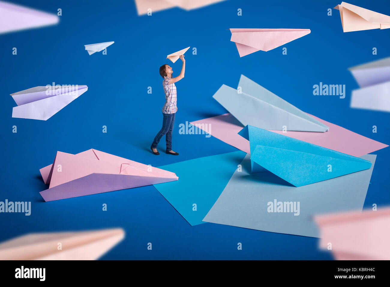 Kreative Surrealismus Design mit Origami Papierflieger. Junges Mädchen lassen Papierflieger. Blau, blau, rosa Origami basteln. Stockfoto