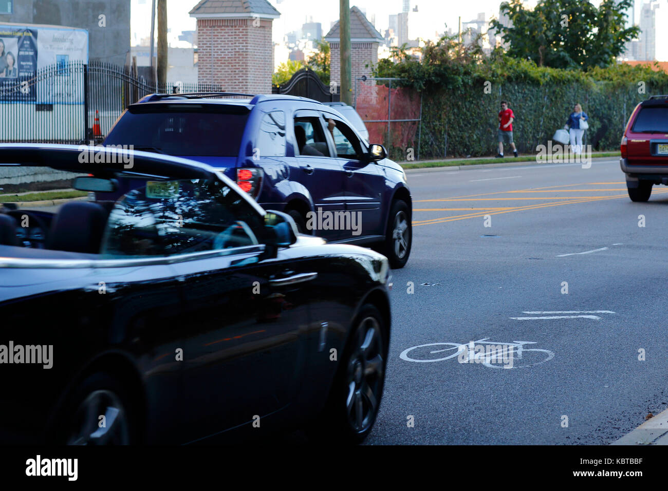 Autos, die auf einer Straße, die mit Radfahrern geteilt wird, rasten, wie mit einem Sharrows-Symbol gekennzeichnet Stockfoto
