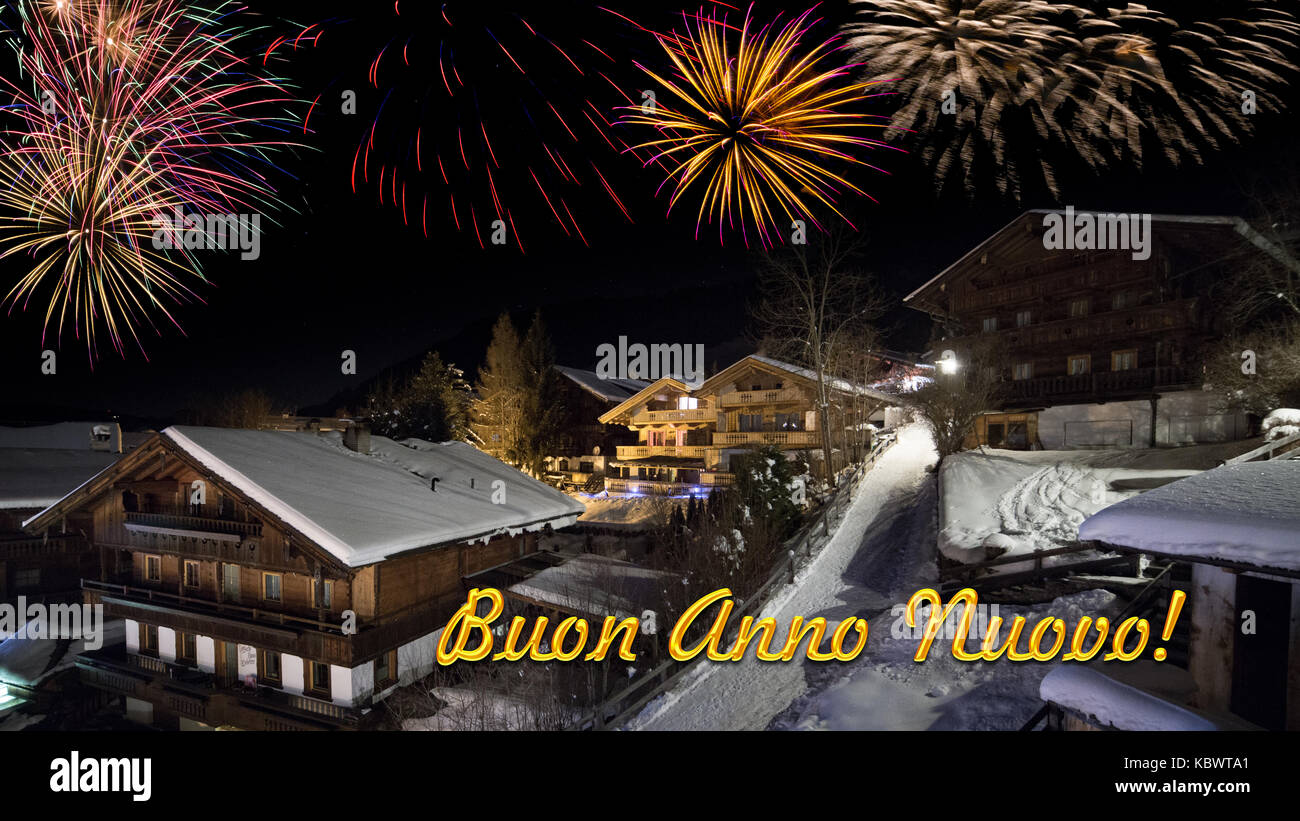 Vorabend des neuen Jahres mit alpinen Dorf im Schnee, Feuerwerk und italienische Text "Buon Anno Nuovo!" Stockfoto