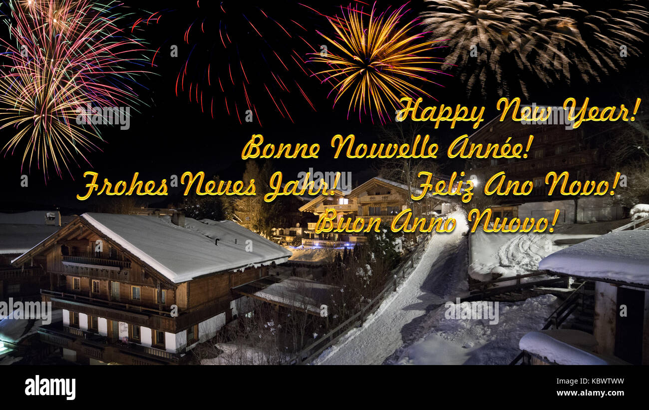 Vorabend des neuen Jahres mit alpinen Dorf im Schnee, Feuerwerk, mulitlingual Begrüßungstext Stockfoto