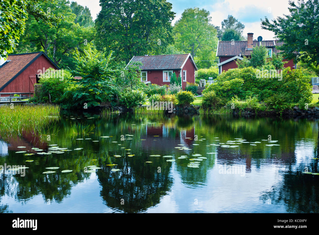 Traditionelles rotes Häuschen neben einem malerischen Teich in Wira Bruk, Schweden Stockfoto