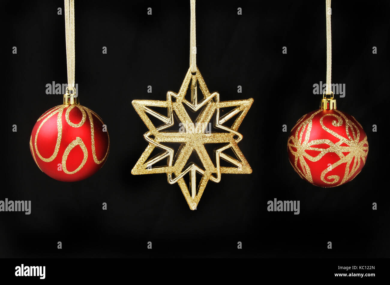 Gold Glitzer Weihnachtsstern und roten und goldenen Kugeln gegen Schwarze isoliert Stockfoto