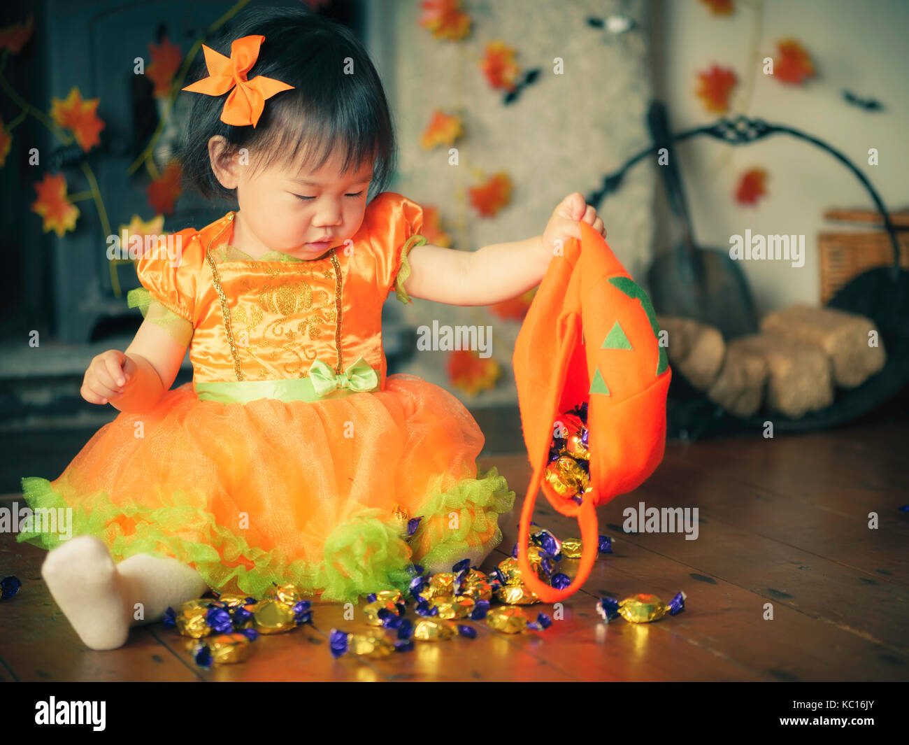 Baby girl gießen Candy auf dem Holzboden Stockfoto
