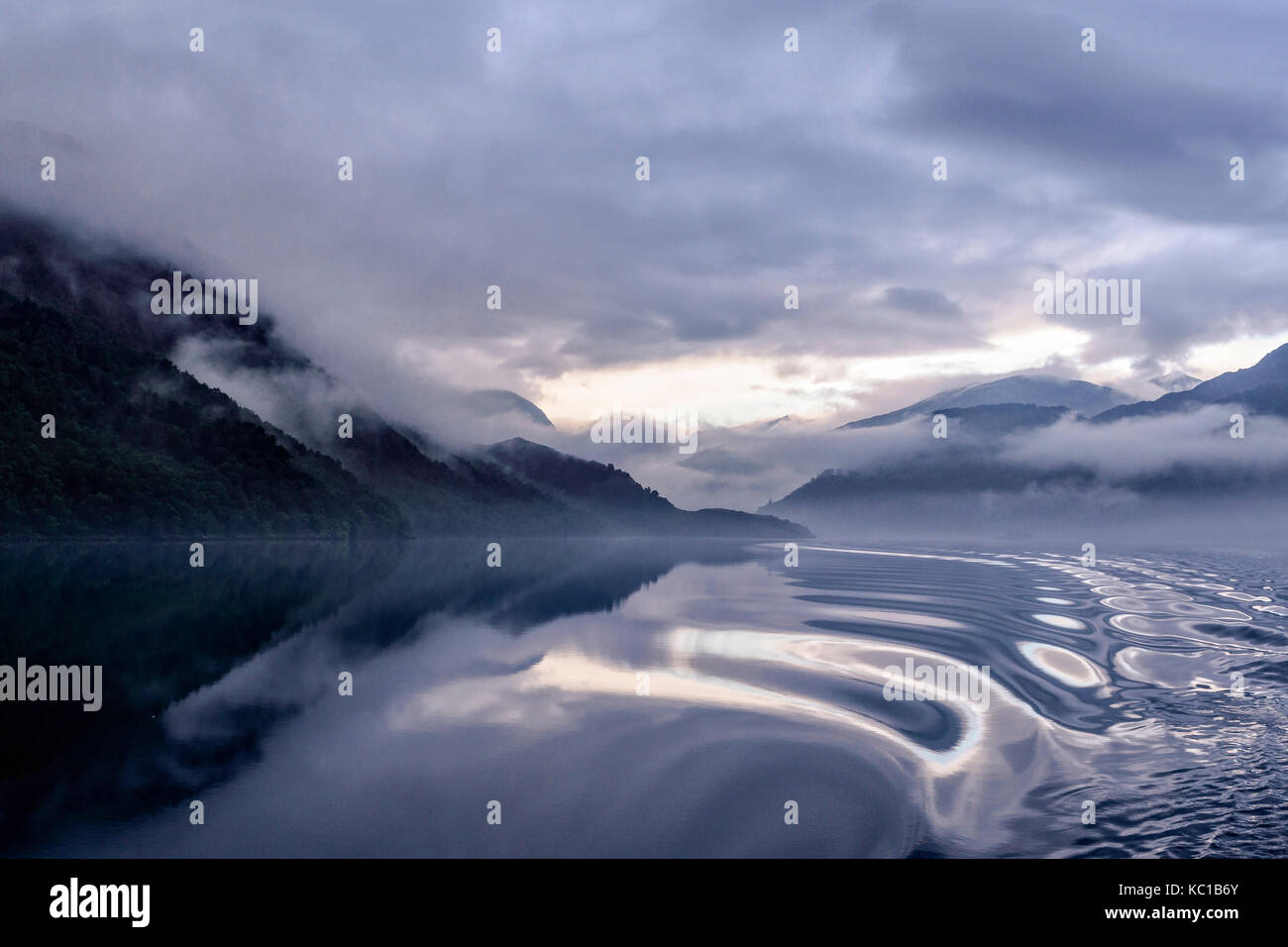 Unheimliche am frühen Morgen Herbst Licht mit Nebel, Reflexionen und Cloud Inversion auf ullswater aus der glenridding genommen Dampfgarer howtown Stockfoto