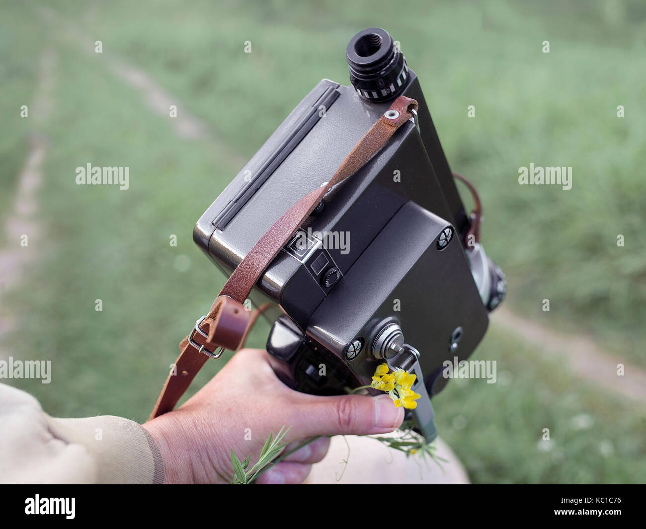 Retro kino Kamera in der Hand der Kameramann. Das grüne Feld im verschwommenen Hintergrund Stockfoto