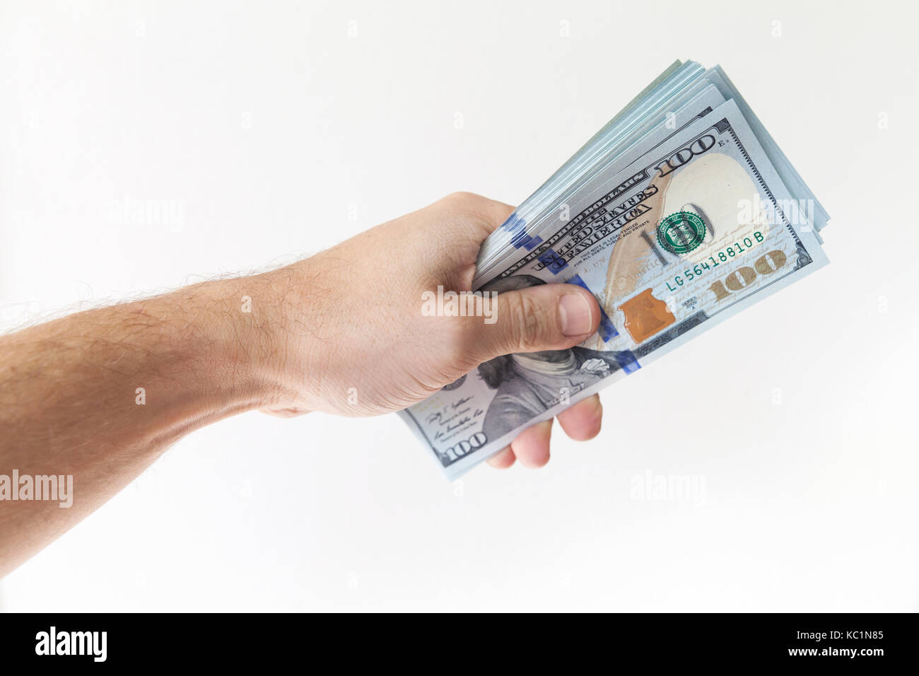 Bündel von einhundert Dollar Noten in männlicher Hand auf weißem Hintergrund Stockfoto