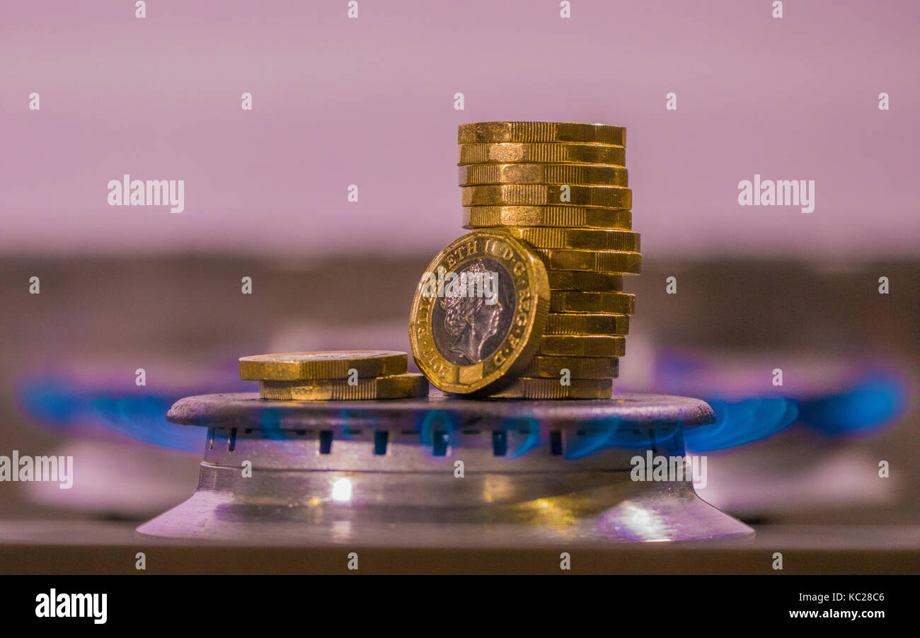 Gasbrenner und neue Pfund Sterling Münzen in einem blauen Flamme. Konzept der UK die Kosten für Kraftstoff, steigende Energiekosten und Zahlungen sowie eine Preisobergrenze. Stockfoto