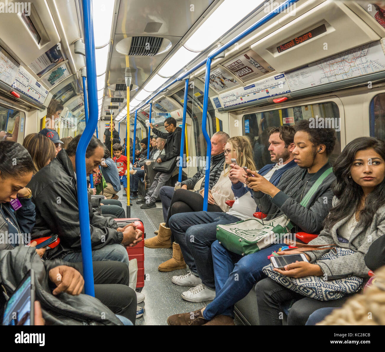 Londoner U-Bahn - Reisende/Pendler innerhalb einer belebten Picadilly Line Schlitten sitzen, während der Rush Hour auf dem Arbeitsweg. England, UK. Stockfoto