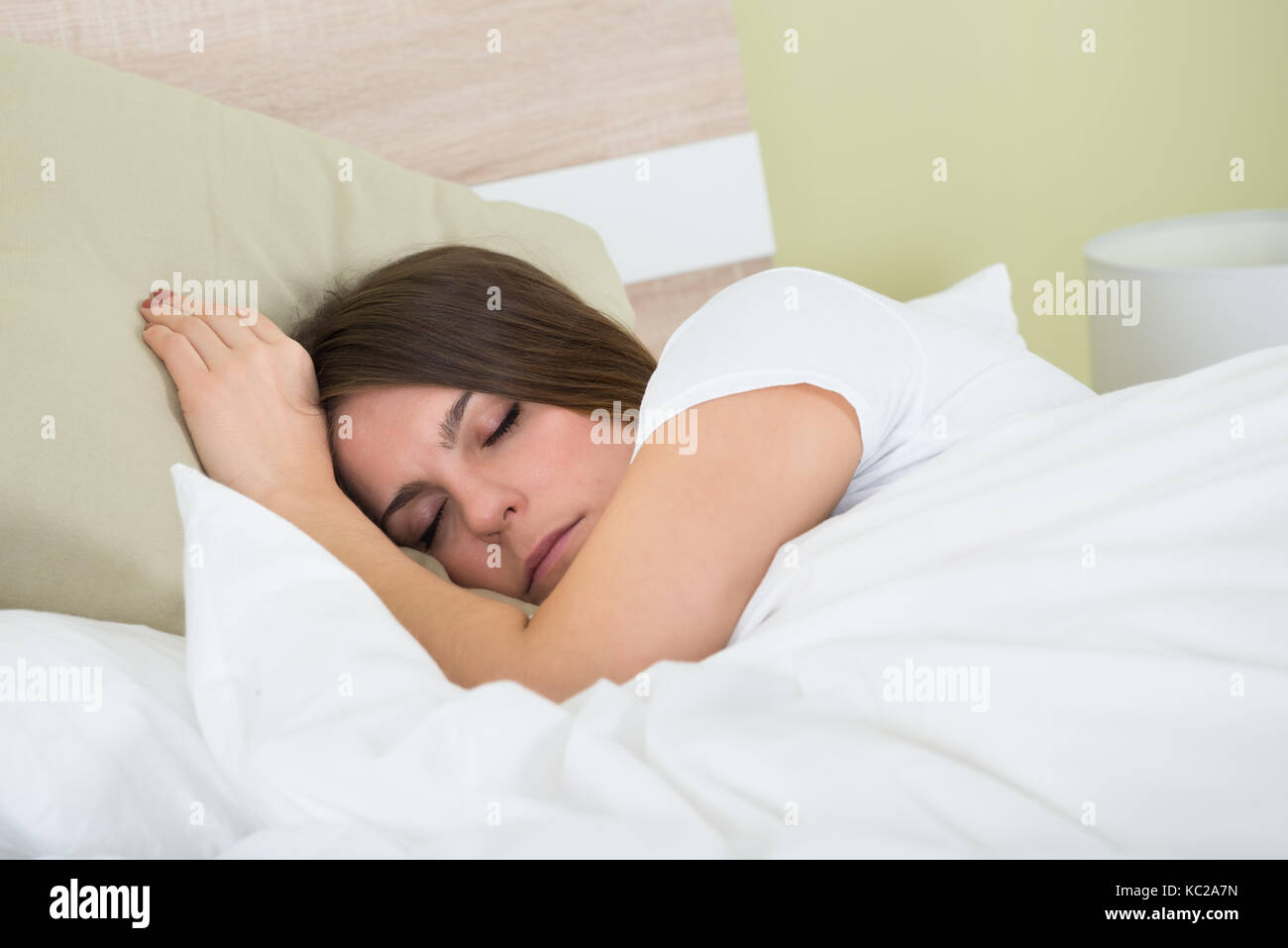 Junge Frau mit Augenmaske während des Schlafens auf dem Bett Stockfoto