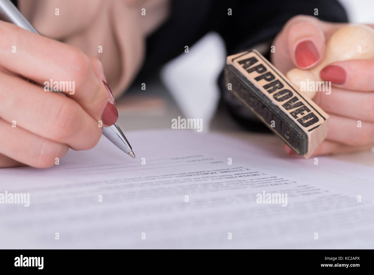 Nahaufnahme der Unternehmer Hand mit Stift und Holz- Stempel auf Dokument Stockfoto