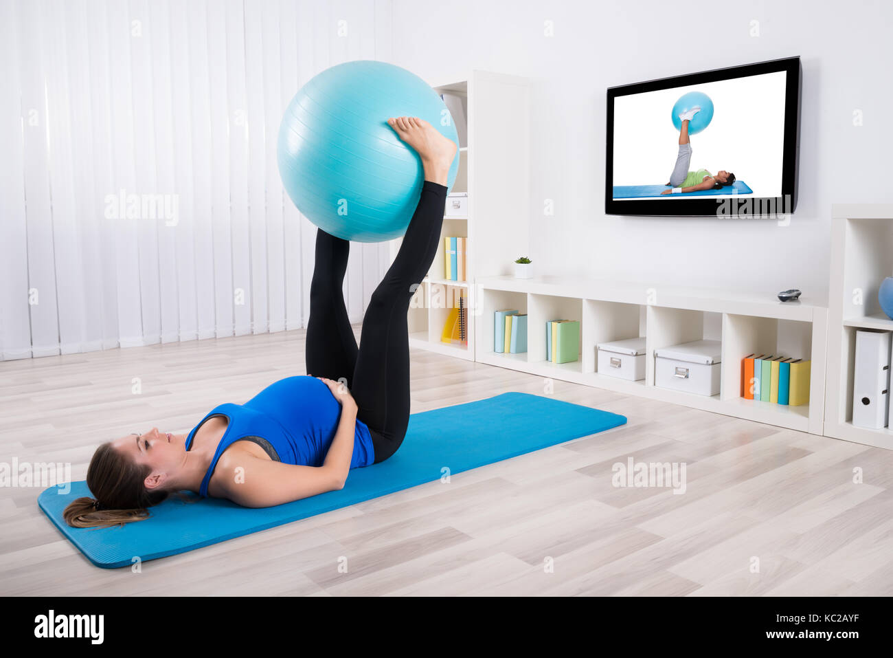 Schwangere Frauen Trainieren mit Fitness Ball vor Fernsehen Stockfoto