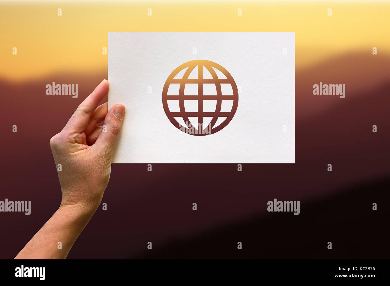 Weibliche Hand, die eine neue leere mit Globus perforiertes Papier Handwerk in Berg Hintergrund Stockfoto