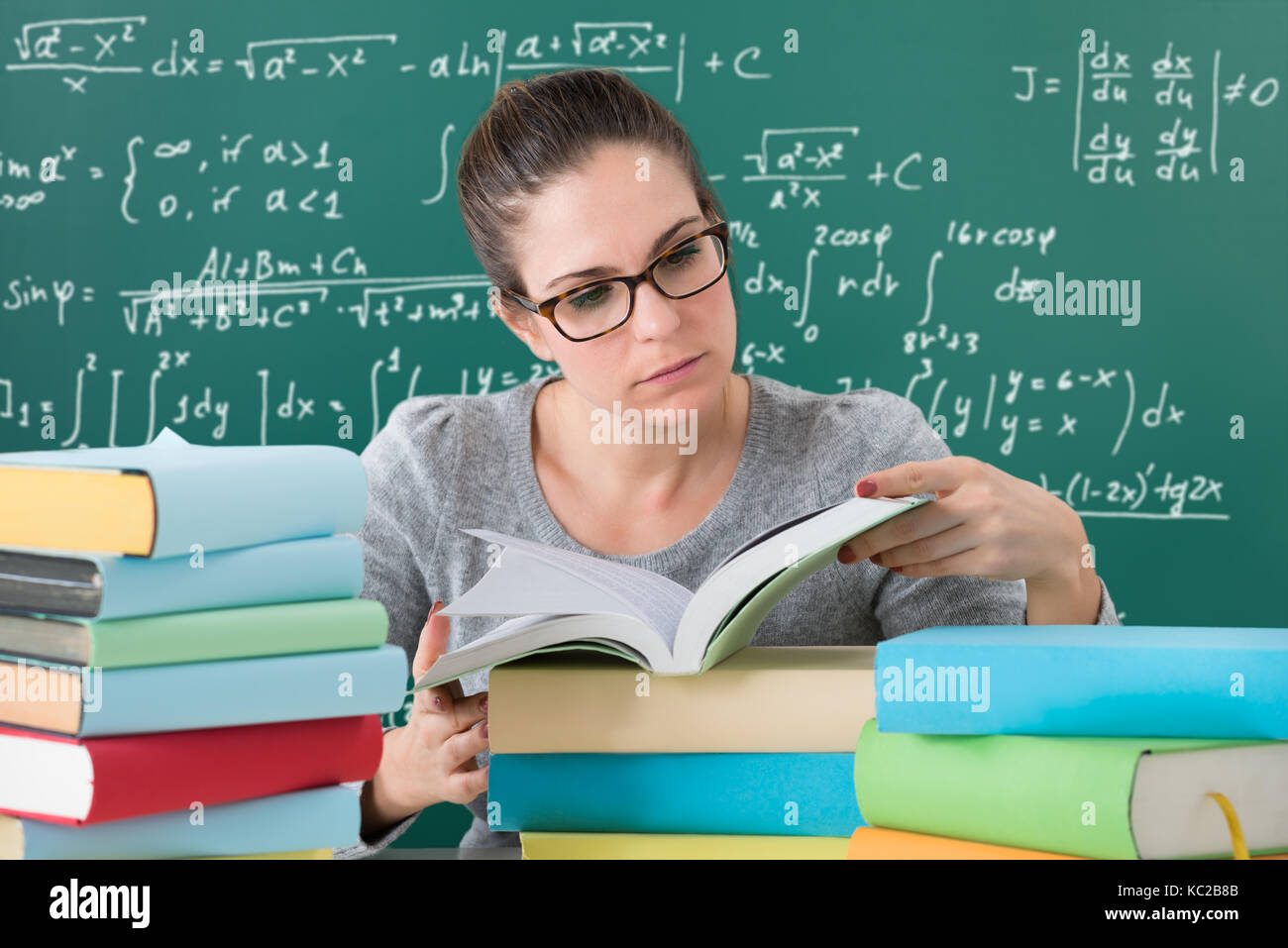 Junge Frau Bücher lesen am Schreibtisch im Klassenzimmer Stockfoto