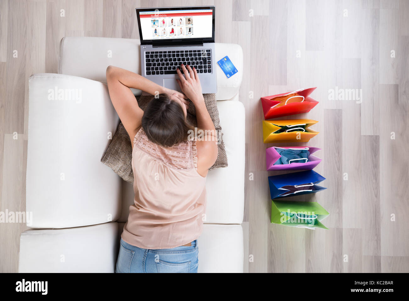 Junge Frau auf Sofa Einkaufen online mit Laptop Stockfoto