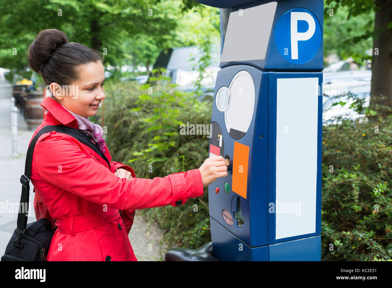 Junge schöne Frau einfügen Münze in Parkuhr Stockfoto