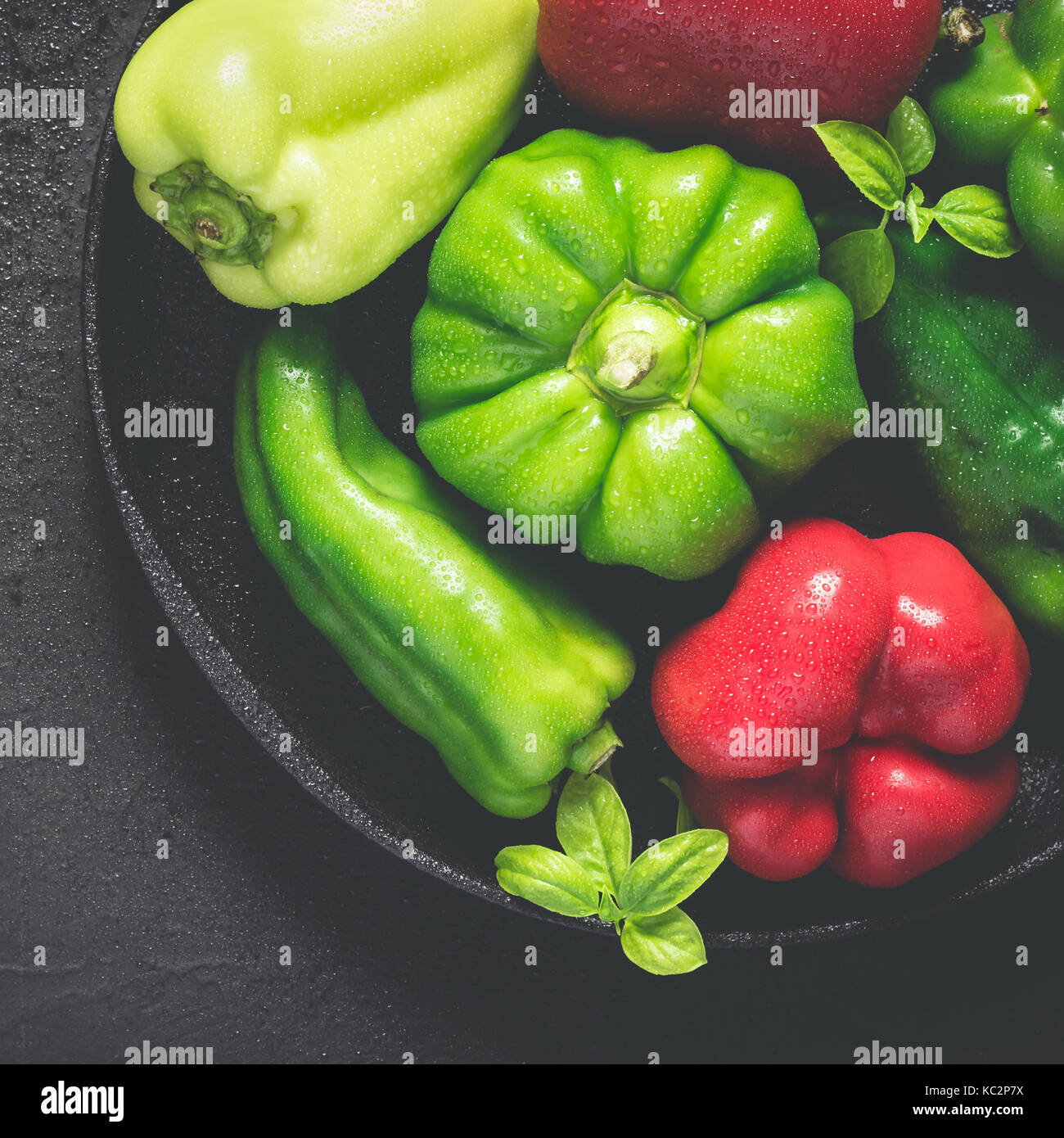 Gusseiserne Schale mit verschiedenen rote und grüne Paprika mit Wassertropfen Nahaufnahme Stockfoto