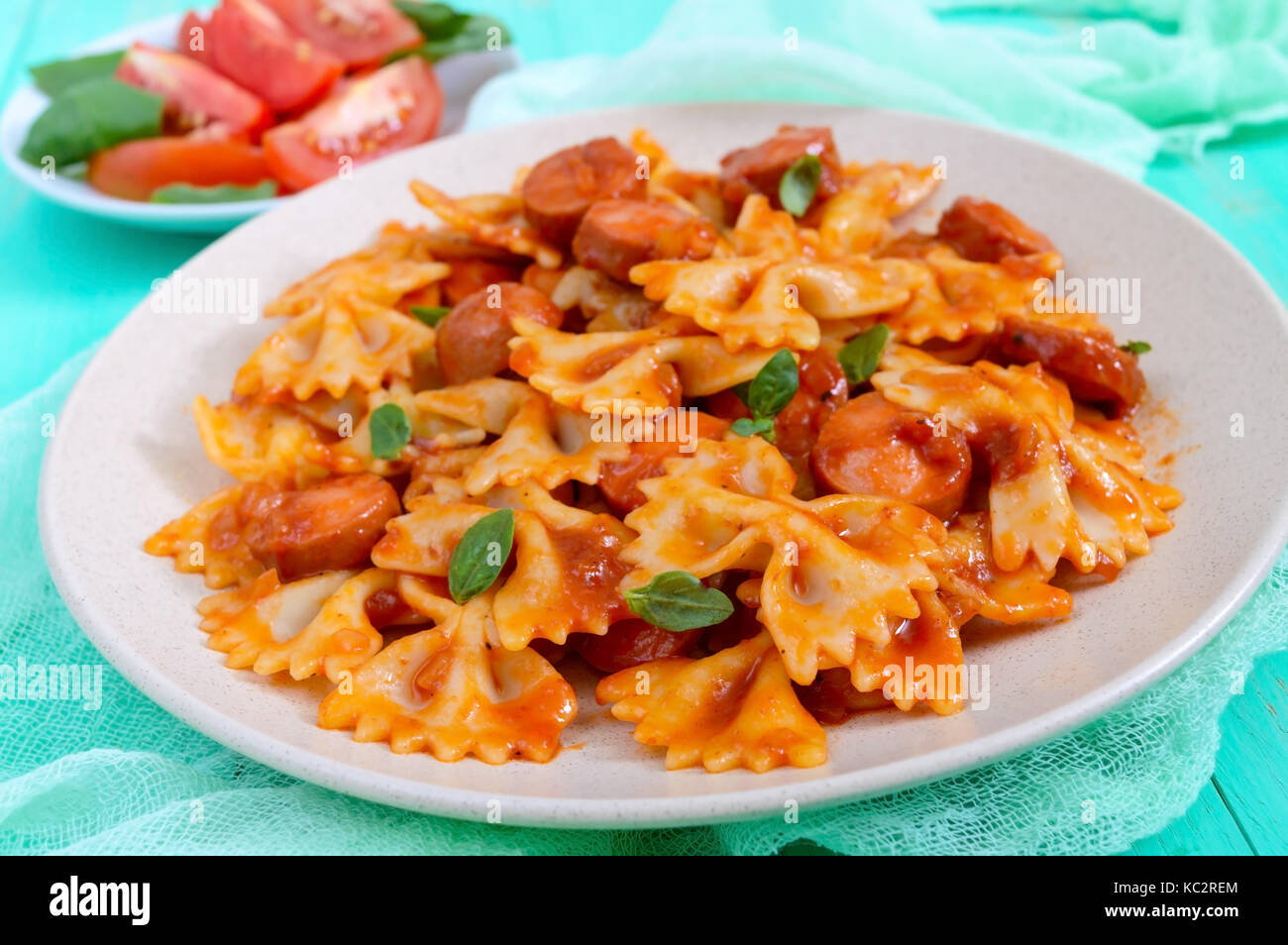 Farfalle Nudeln mit Klumpen Wurst in Tomatensauce auf einem hellen ...