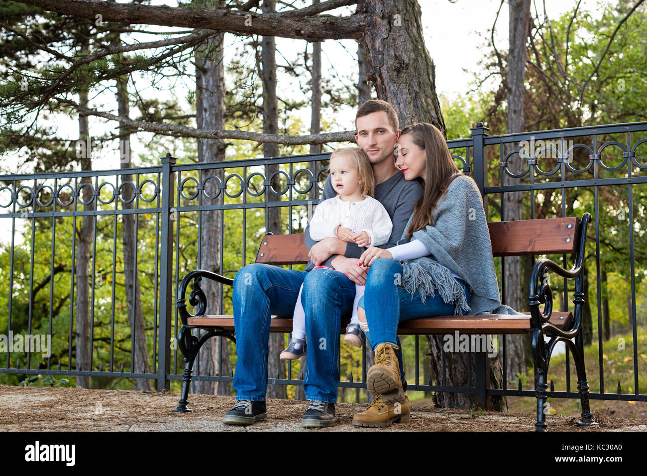 Glückliche Familie von drei sitzen auf einer Bank in einem Park ihre Zeit zusammen genießen. Stockfoto