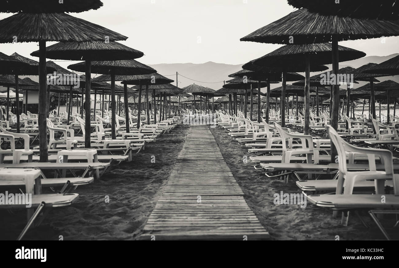 Details der griechischen Stränden, Holz- Reed Sonnenschirme und Betten in Schwarz und Weiß. Stockfoto