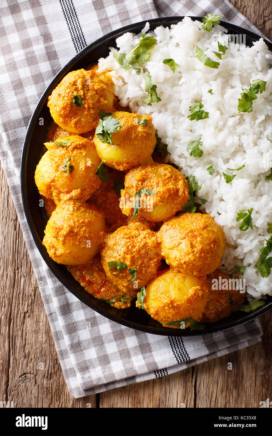 Indisches essen: Dum aloo Kartoffeln in Sauce mit Reis close-up auf einem Tisch. Senkrechte Draufsicht von oben Stockfoto