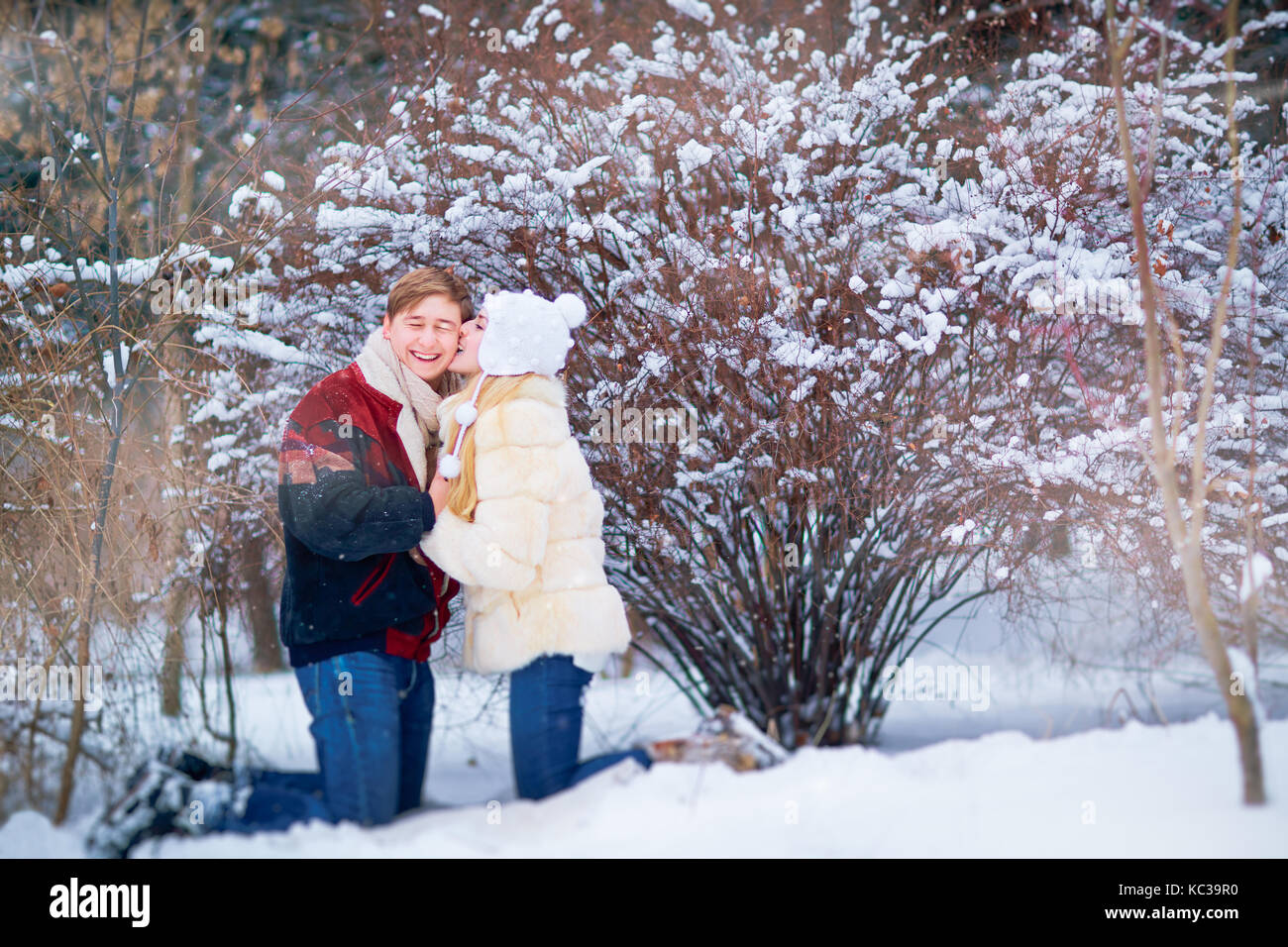 Junges Paar umarmen auf Schnee im Park im Winter Stockfoto