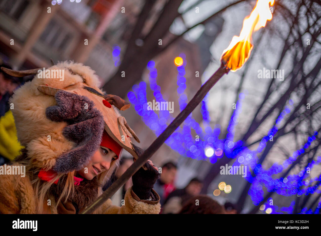 Pernik, Bulgarien - Januar 27, 2017: wunderschöne Mädchen sucht unter Ihrem scary Maske und lächelnd, während sie brennende Fackel an surva, der Internat Stockfoto