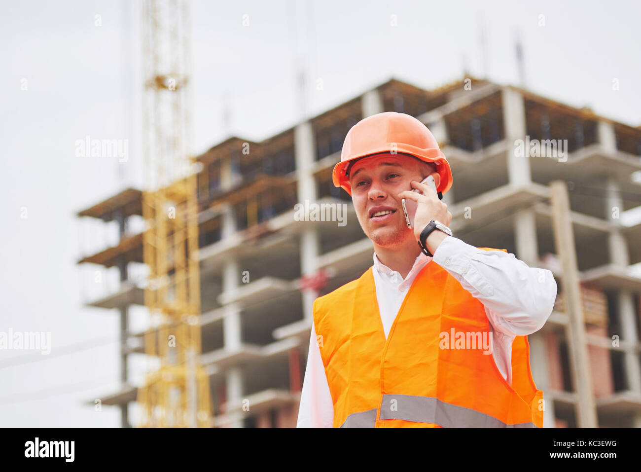 Der junge Architekt trägt einen Schutzhelm auf die Berge Gebäude im Hintergrund Stockfoto